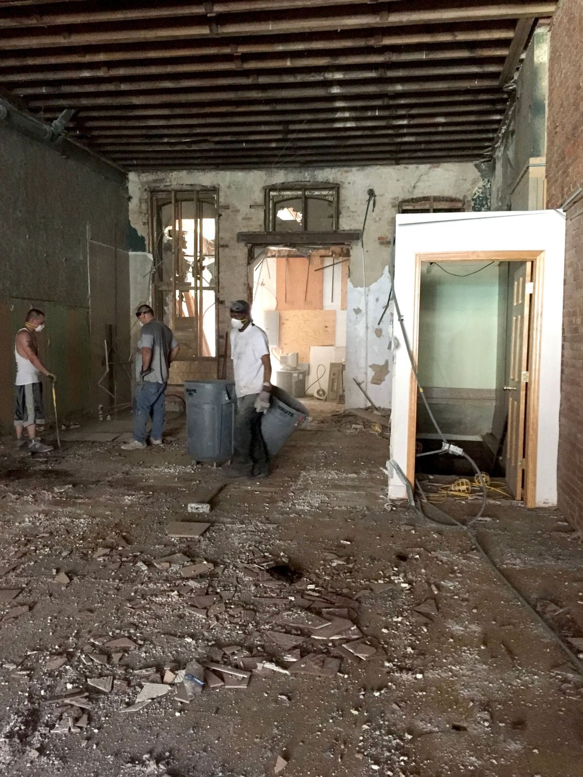 Gather on Central during demolition: bare joists, debris on the floor, and workers clearing the space