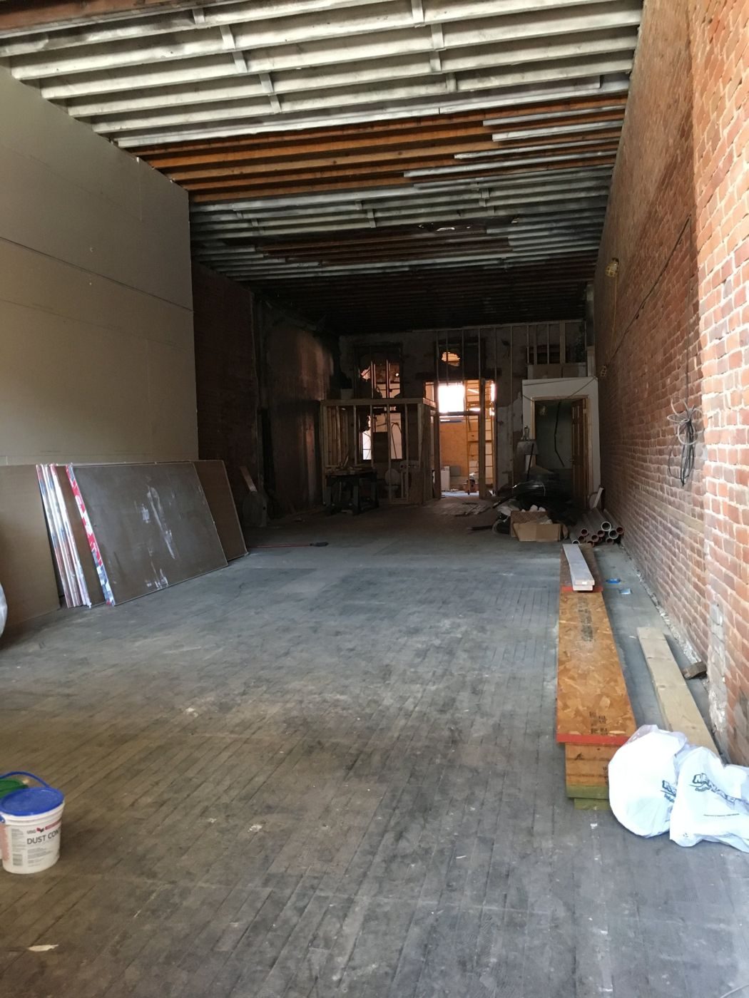 Gather on Central mid-renovation: open joists, brick wall, and building materials stacked on the floor
