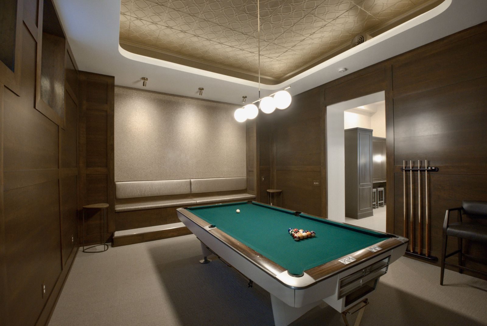 Lower-level game room with a pool table, wood paneling, and a decorative tin ceiling