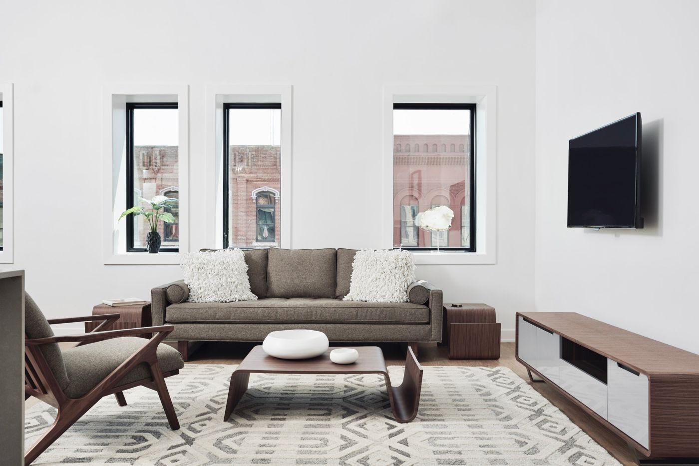 The same front room today: a bright living room with a sofa beneath the street-facing windows