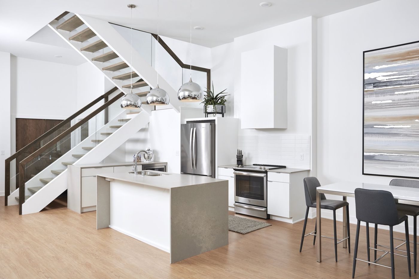 New kitchen with a waterfall island, stainless appliances, and an open staircase