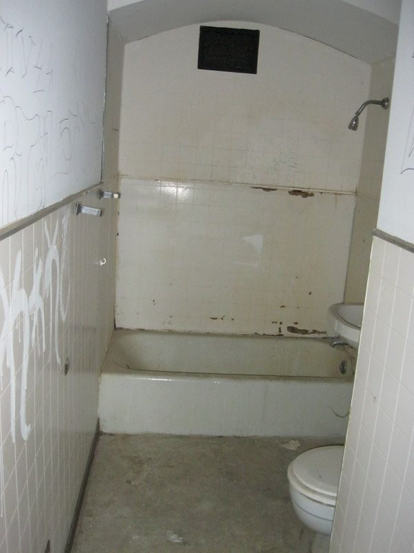 Old bathroom before: stained tub and graffiti on the tile