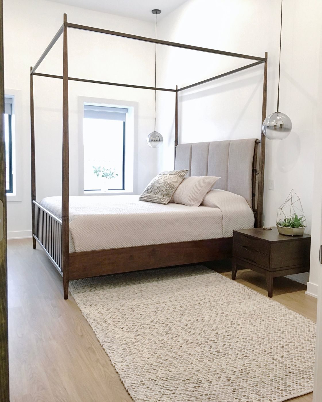 Finished bedroom with a canopy bed and pendant lights
